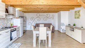 Una cocina moderna con vigas de madera, una mesa de comedor con sillas, un refrigerador y una estufa.