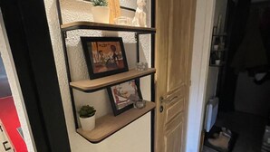 A hallway with a shelf unit containing a plant, a framed picture, and a small figurine.