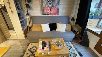 Un soggiorno con un divano grigio, un tavolino da caffè con libri e una ciotola decorativa, una libreria e un murale raffigurante un cervo.
