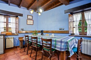 A dining area with a table set for four, wooden chairs, a coffee machine, and a radiator.