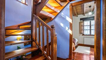 A wooden staircase with a view to a room with a bed and a radiator.