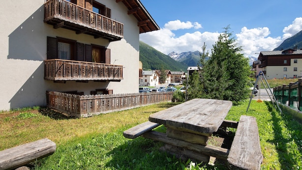 Un bâtiment doté de balcons, d’une table de pique-nique et ayant une chaîne de montagnes en toile de fond.