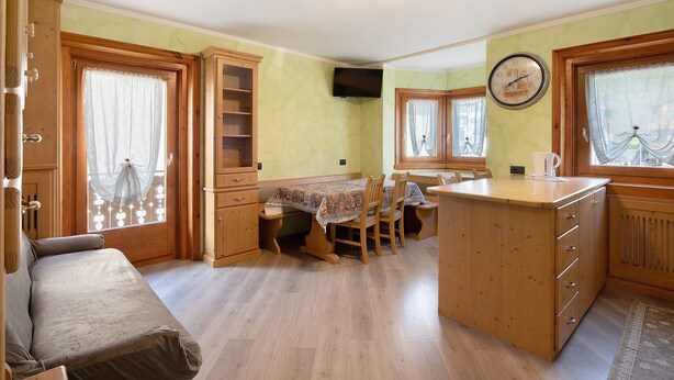A compact kitchen with wooden cabinets, a dining table, and a built-in refrigerator.
