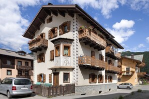Un edificio a più piani con balconi, persiane di legno e fioriere.