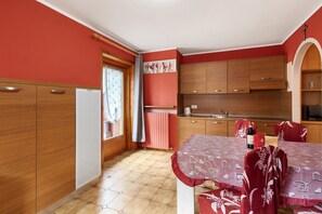 Una cucina compatta con mobili in legno, un tavolo da pranzo con tovaglie rosse e una finestra con tende.