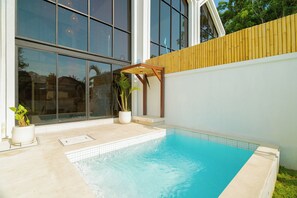 Una piscina moderna al aire libre con un deck de madera y plantas en macetas.