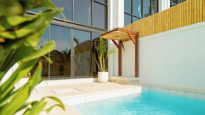Una piscina interior moderna con agua azul cristalina, rodeada de amplios ventanales y una pérgola de madera.