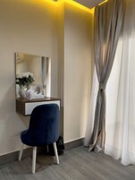 Una habitación con escritorio, silla, espejo y ventana con cortinas.