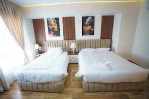 A hotel room with two beds, a wooden floor, and artwork on the walls.
