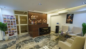 A reception area with a wooden reception desk, a glass coffee table, and two white armchairs.