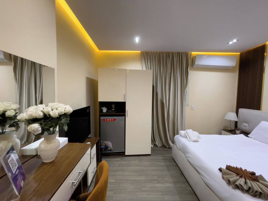Habitación de hotel con cama, escritorio con computadora, refrigerador y armario.