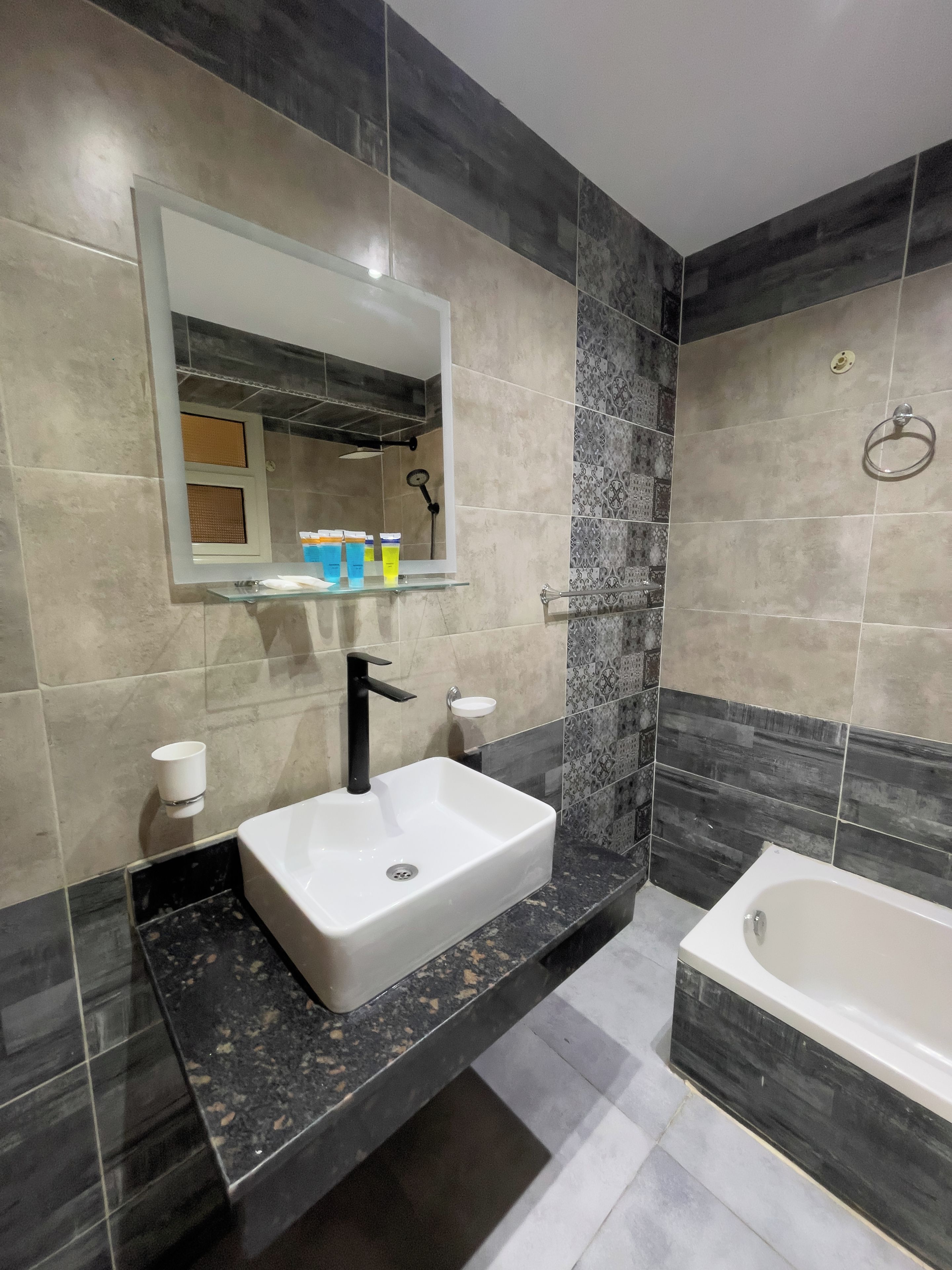 Un baño moderno con un lavamanos blanco, grifo negro y una bañera.
