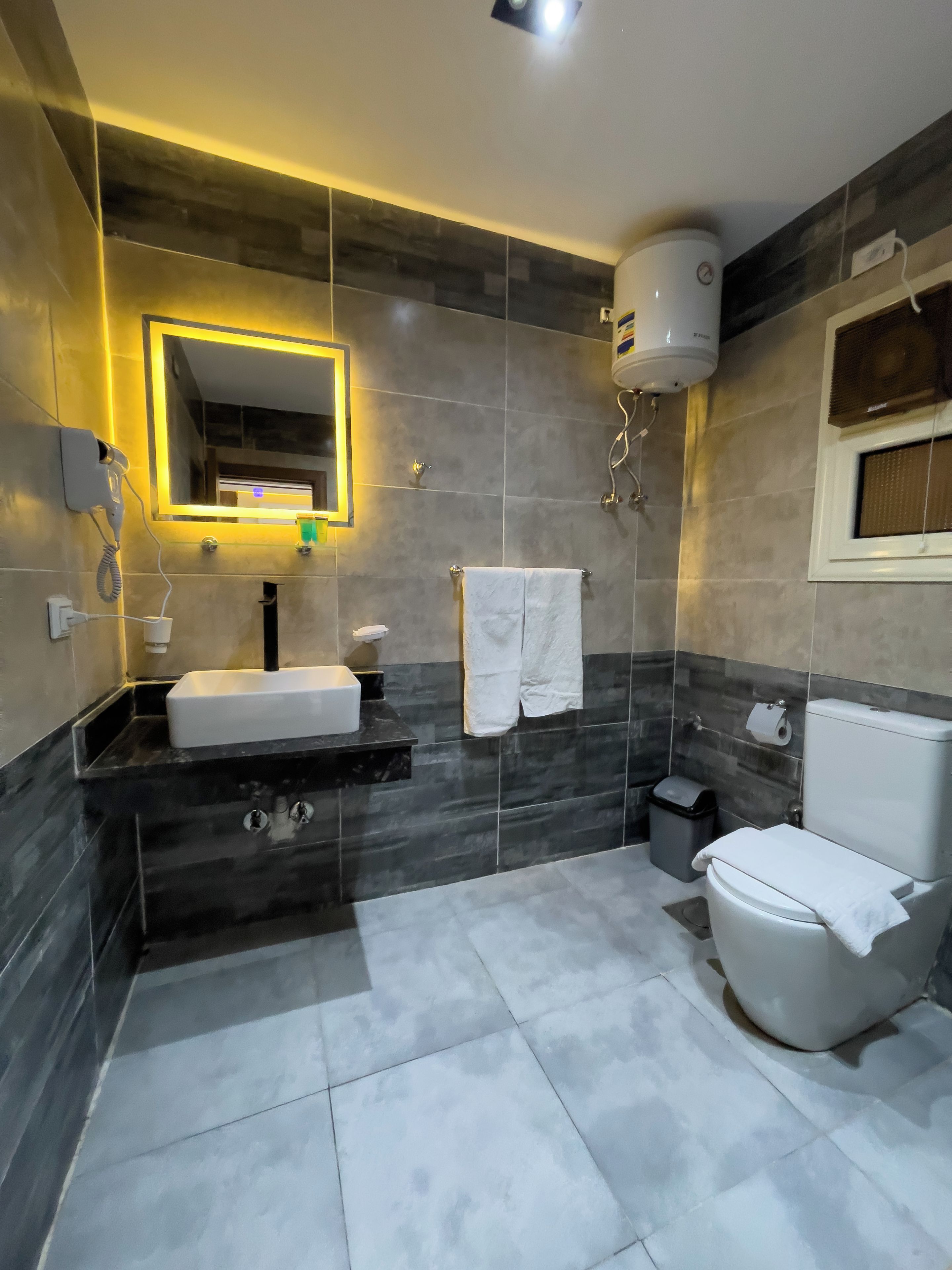 Et moderne badeværelse med en indbygget vask, et spejl, et toilet og et bruseområde.