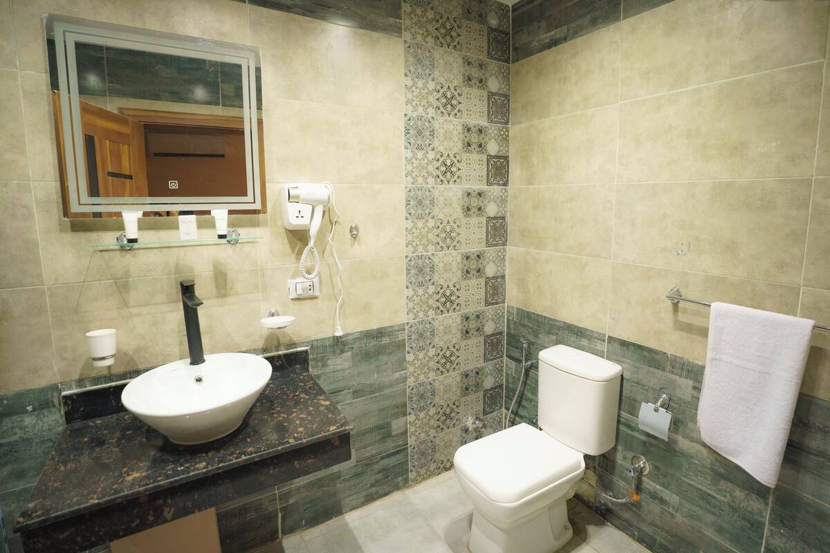 A bathroom with a sink, mirror, toilet, and towel rack.