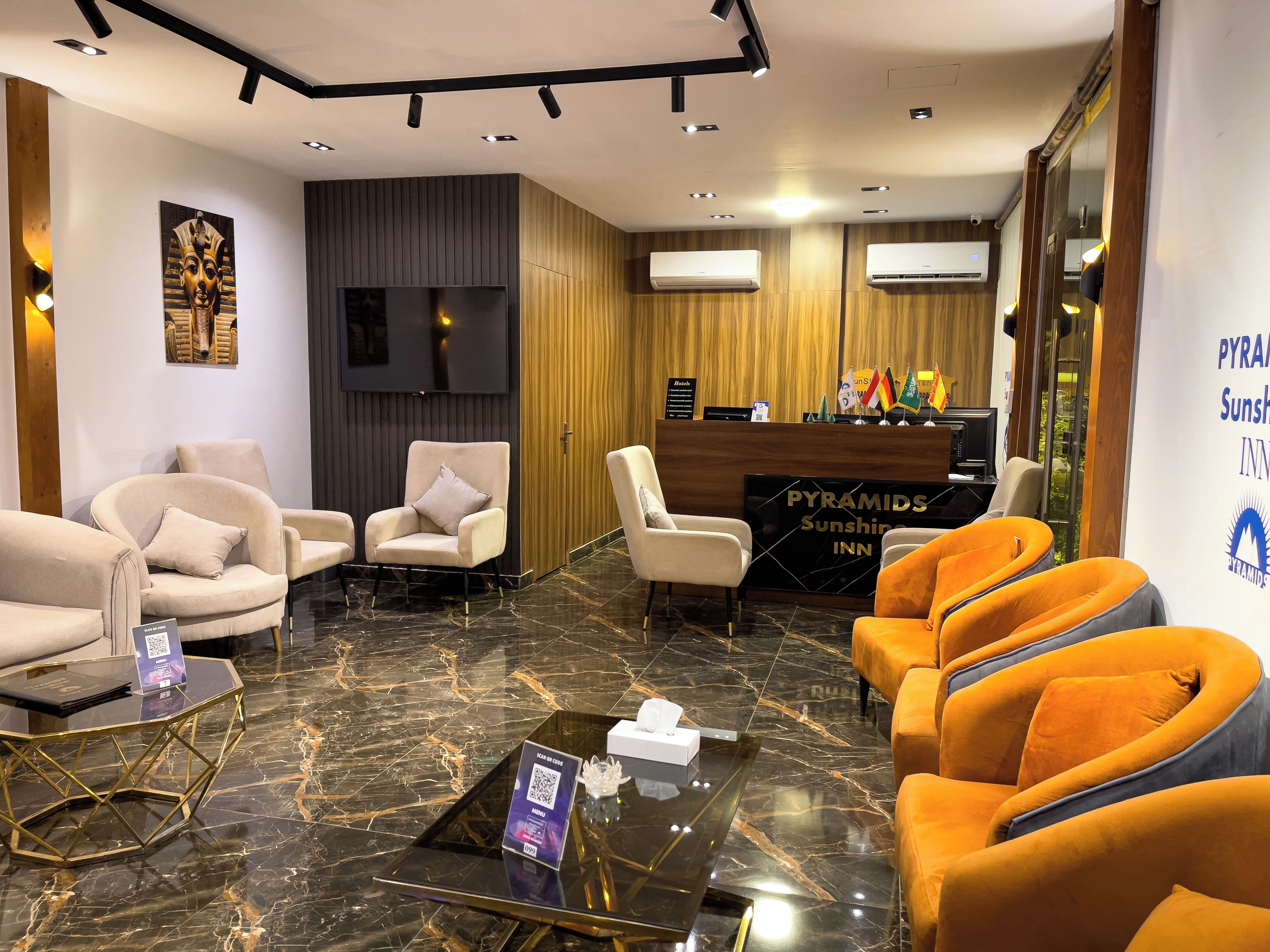 Un vestíbulo de hotel con zonas de estar, mostrador de recepción y una pantalla de televisión grande.