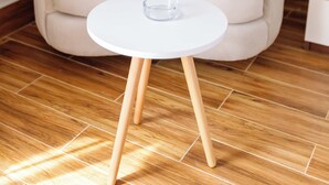 A beige armchair with a round white table in front of it.