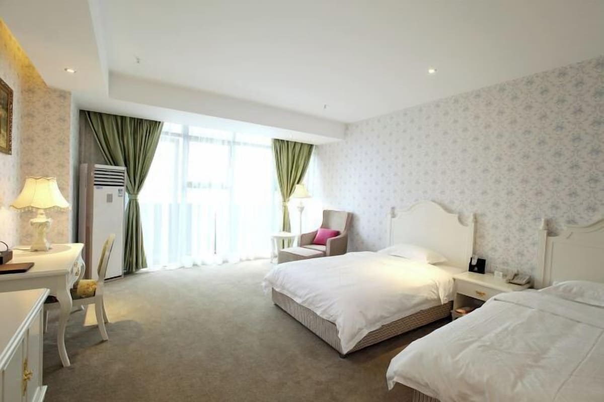 Ein Hotelzimmer mit einem großen Bett, einem Schreibtisch mit Lampe, einem Sessel und einem kleinen Tisch.