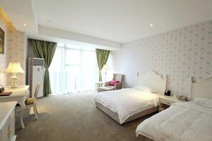 Ein Hotelzimmer mit einem großen Bett, einem Schreibtisch mit Lampe, einem Sessel und einem kleinen Tisch.