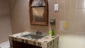 A bathroom with a sink, mirror, and green flower-patterned tiles. - Económico y Céntrico Departamento a Solo 15mtrs de la Playa (Puerto Vallarta)