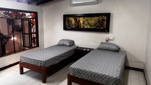 A room with two wooden beds, a ceiling fan, an air conditioner, and a window with a decorative view. - Económico y Céntrico Departamento a Solo 15mtrs de la Playa (Puerto Vallarta)