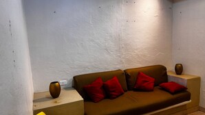 A cozy living room with a brown sofa, red cushions, a small table with a vase, and a lamp. - Económico y Céntrico Departamento a Solo 15mtrs de la Playa (Puerto Vallarta)