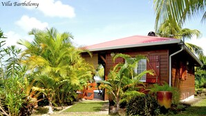 A wooden villa with a red roof, surrounded by lush tropical vegetation. - Charmant Chalet Créole Avec sa Piscine Privée (Goyave)