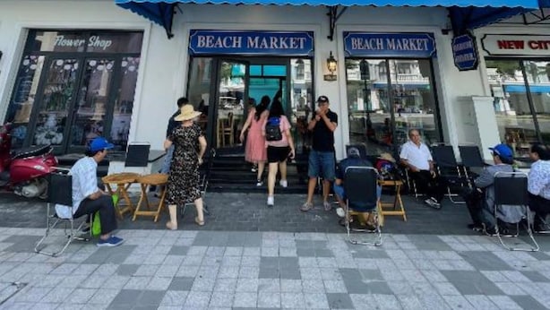 A beachfront building with a 'Beach Market' sign, outdoor seating, and a 'Flower Shop' across the street. - The Beach Homestay (Phu Quoc)