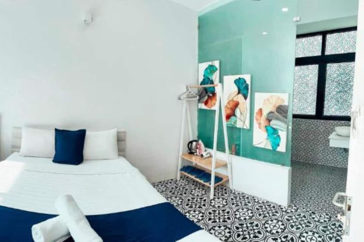 A hotel room with two beds, a small round table, and artwork on the wall.