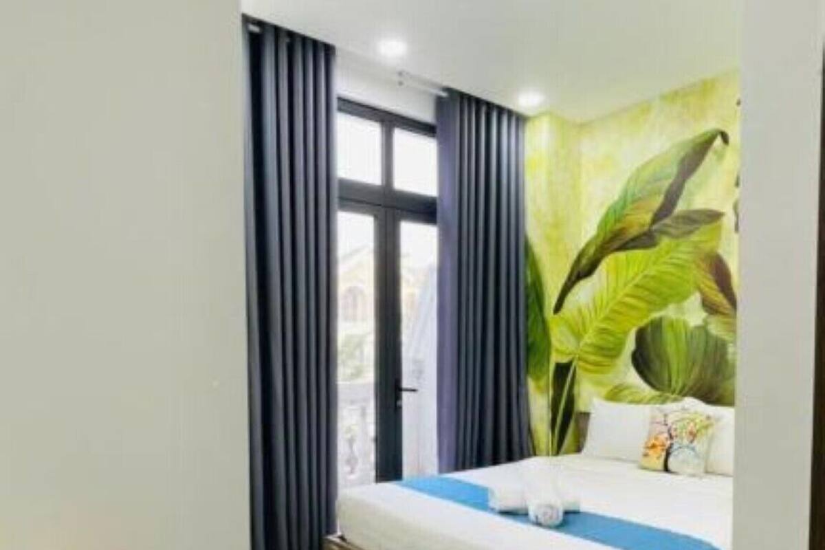A hotel room with a bed, a desk with a lamp, and a large window with curtains.
