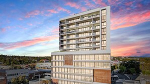 A modern multi-story building with a flat roof and large windows, surrounded by other buildings and a parking lot. - Executive Rental - Campbelltown (Campbelltown)