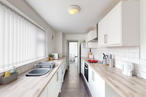 A modern kitchen with white cabinets, a wooden countertop, a built-in oven, and a sink.