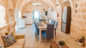 Un coin repas chaleureux avec un mur en pierre, une table en bois et des chaises bleues.