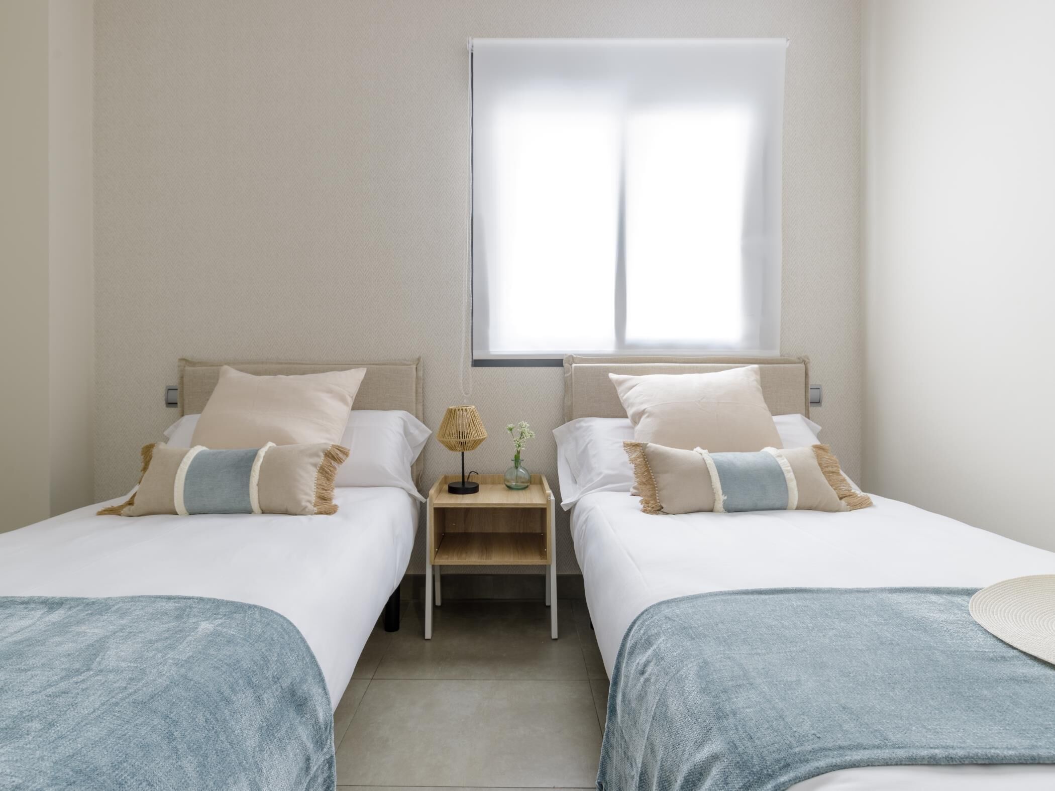 Habitación doble con dos camas, una mesita y una ventana.