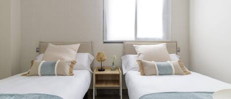 Habitación doble con dos camas, una mesita y una ventana.