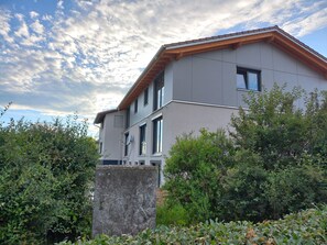 Ein modernes, zweistöckiges Gebäude mit Flachdach, großen Fenstern und einem sichtbaren Stromkasten.