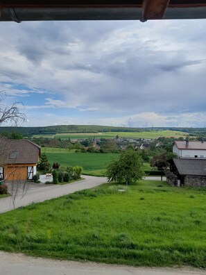 Un paysage rural avec une route, des champs verdoyants et quelques bâtiments.