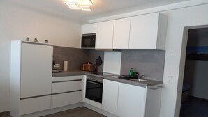 Una cocina moderna con armarios blancos, horno empotrado, microondas y fregadero.