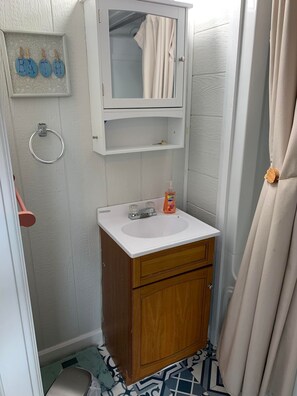 A small bathroom with a wooden cabinet, a white sink, a mirror, and a towel rack.