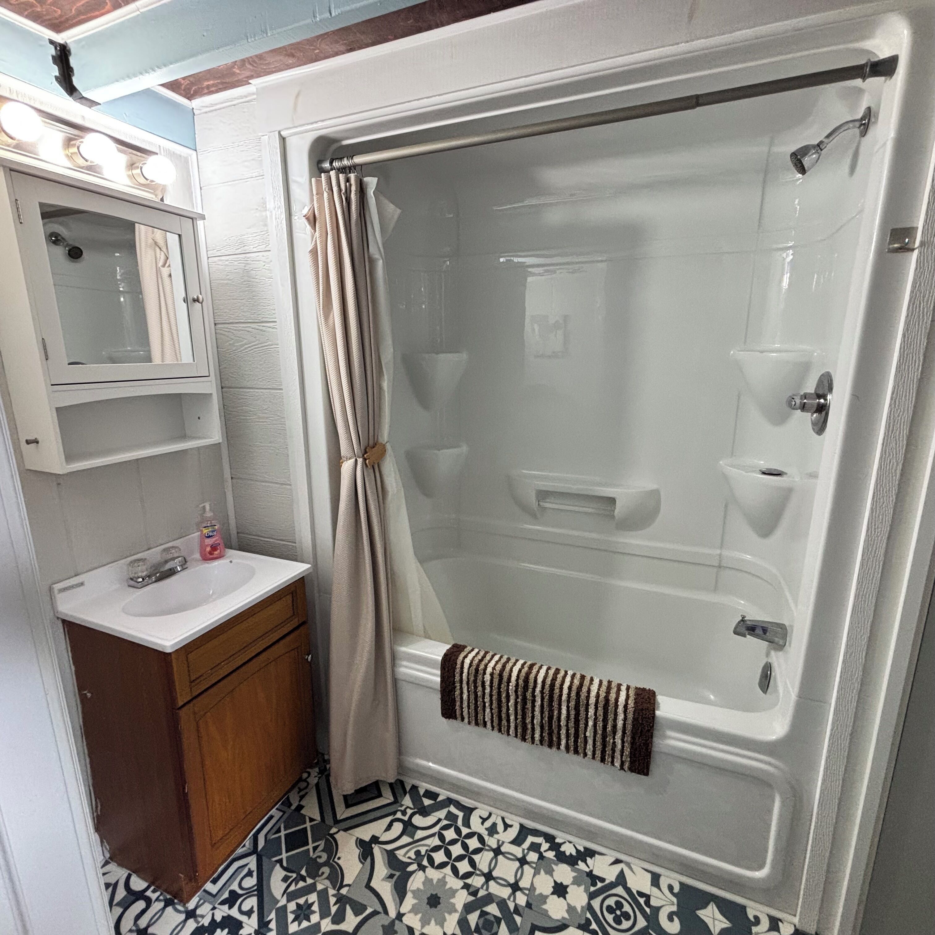 A bathroom with a bathtub, a sink, a mirror, and a shower curtain.