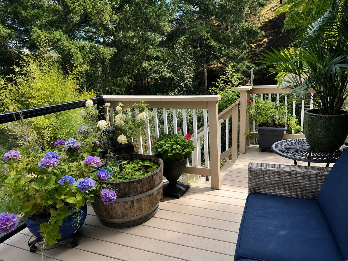 A wooden deck with outdoor furniture, potted plants, and a white railing.