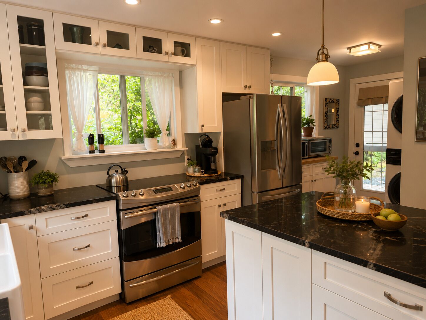 A modern kitchen with white cabinetry, stainless steel appliances, and a black countertop.