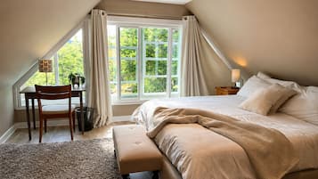 Een slaapkamer met een groot bed, een bureau en een stoel.