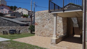 A stone building with a balcony, outdoor seating, and a paved patio area.
