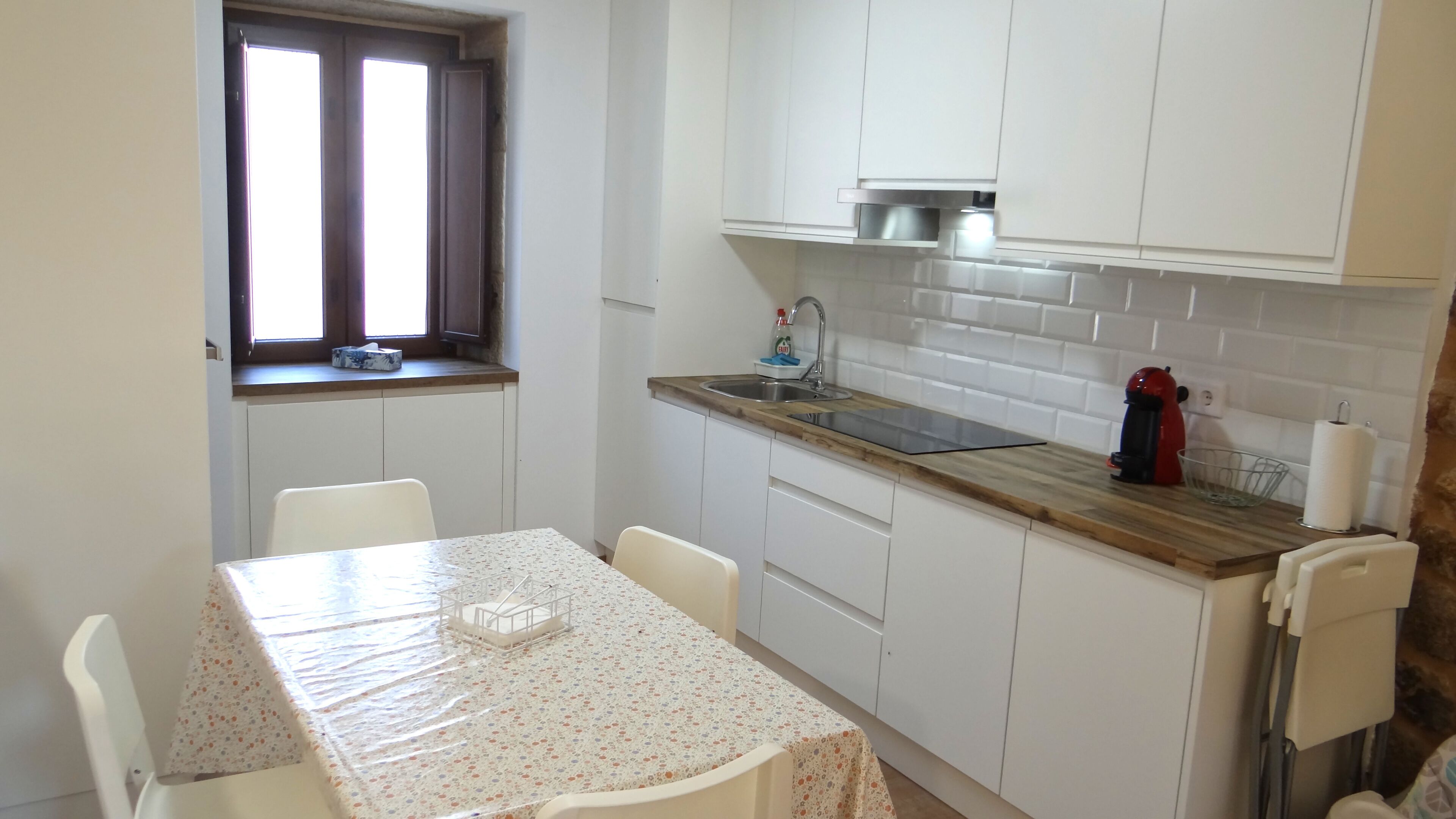 A compact kitchen with white cabinets, a wooden countertop, and a small window.
