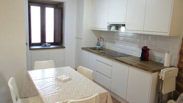 A compact kitchen with white cabinets, a wooden countertop, and a small window.