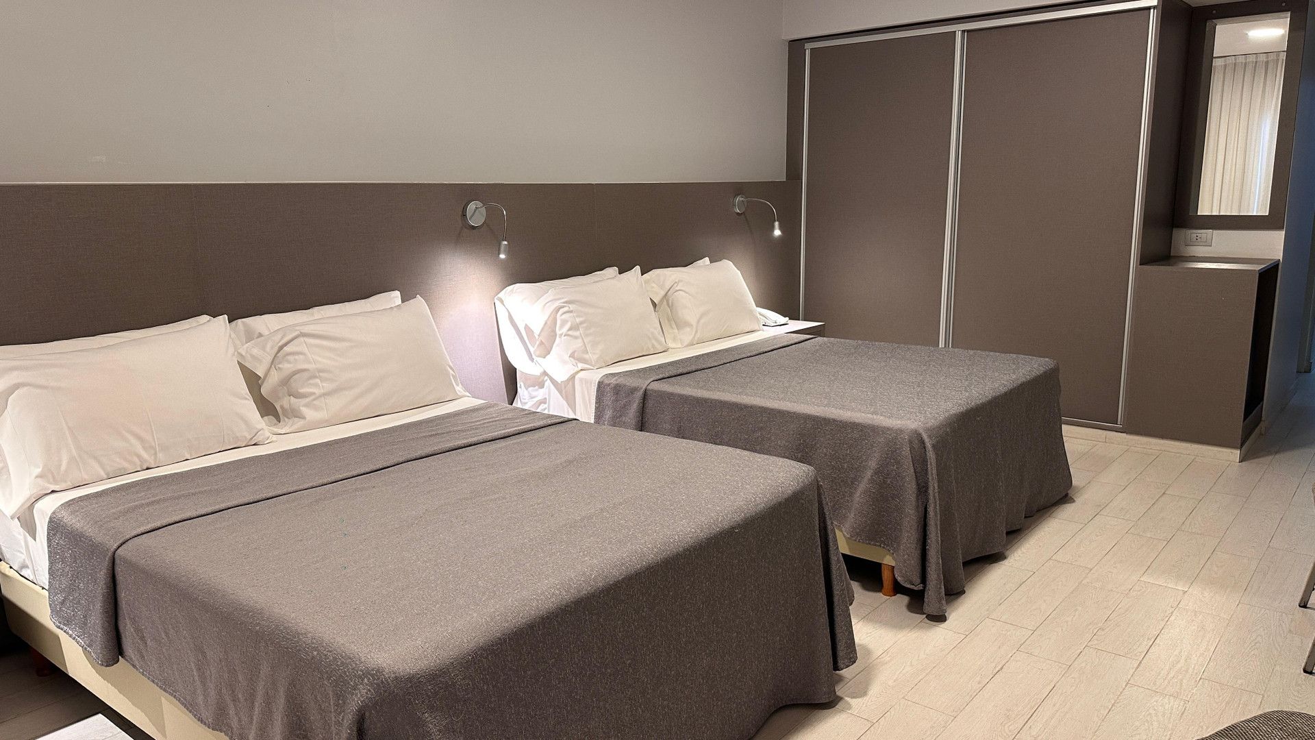 Ein Hotelzimmer mit zwei Betten, einem Kleiderschrank und einem Spiegel.