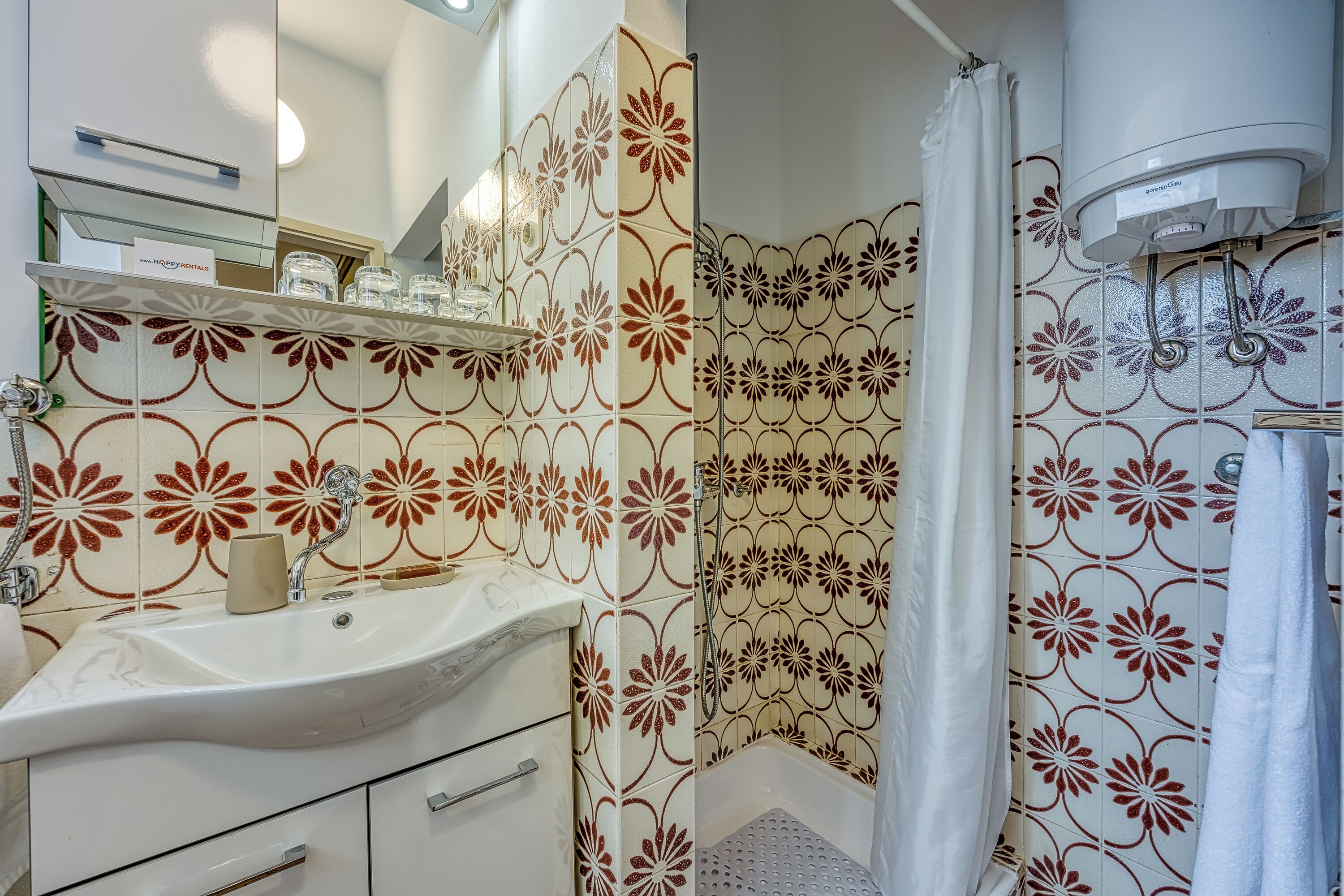 Un baño con lavamanos blanco, espejo y cortina de ducha.