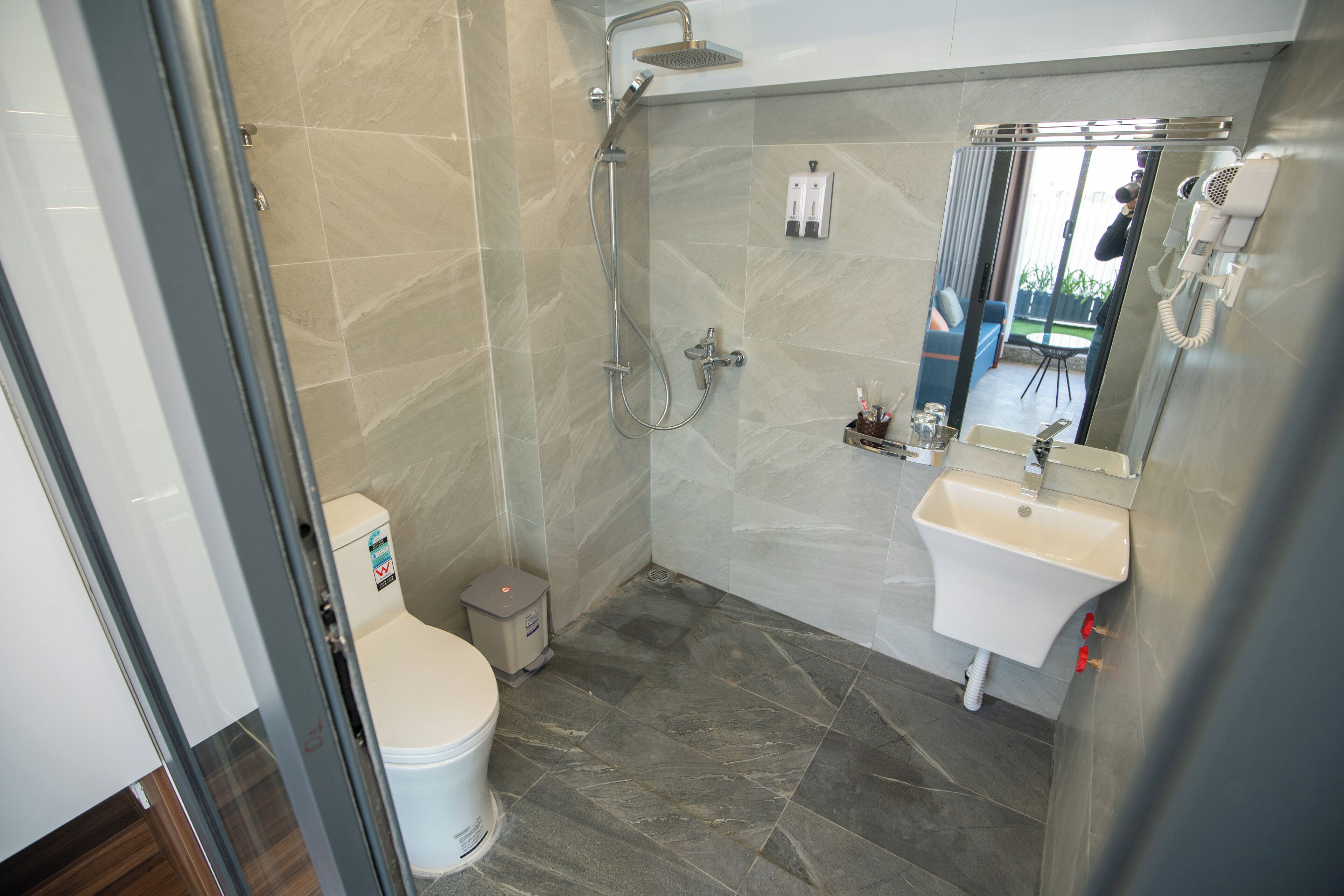 Une salle de bain moderne équipée d’une douche, de toilettes, d’un lavabo et d’un miroir.