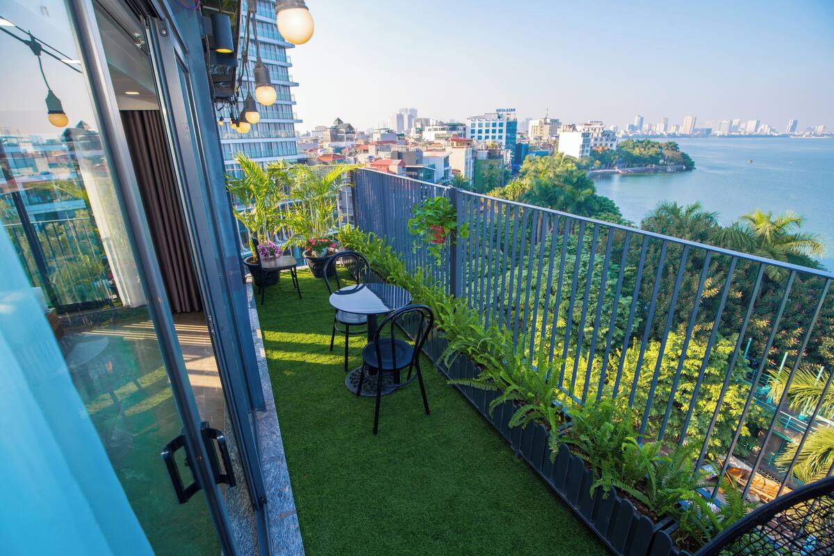 A balcony with artificial grass, a table, chairs, and potted plants.