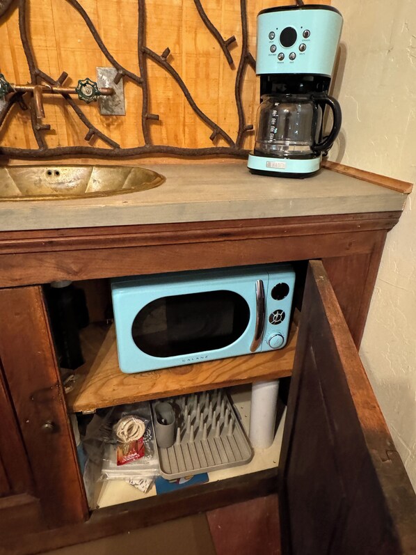 A kitchen with a sink, a coffee maker, and a microwave built into a wooden cabinet. - Rustic, Artsy Studio w/ Desert Panoramic Views (Black Canyon City)